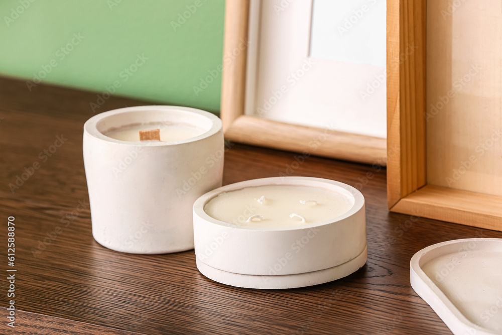 Holders with candles on table near color wall in room, closeup