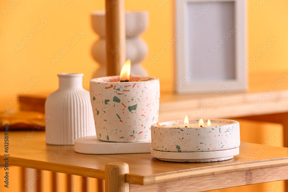 Holders with burning candles on table in room, closeup