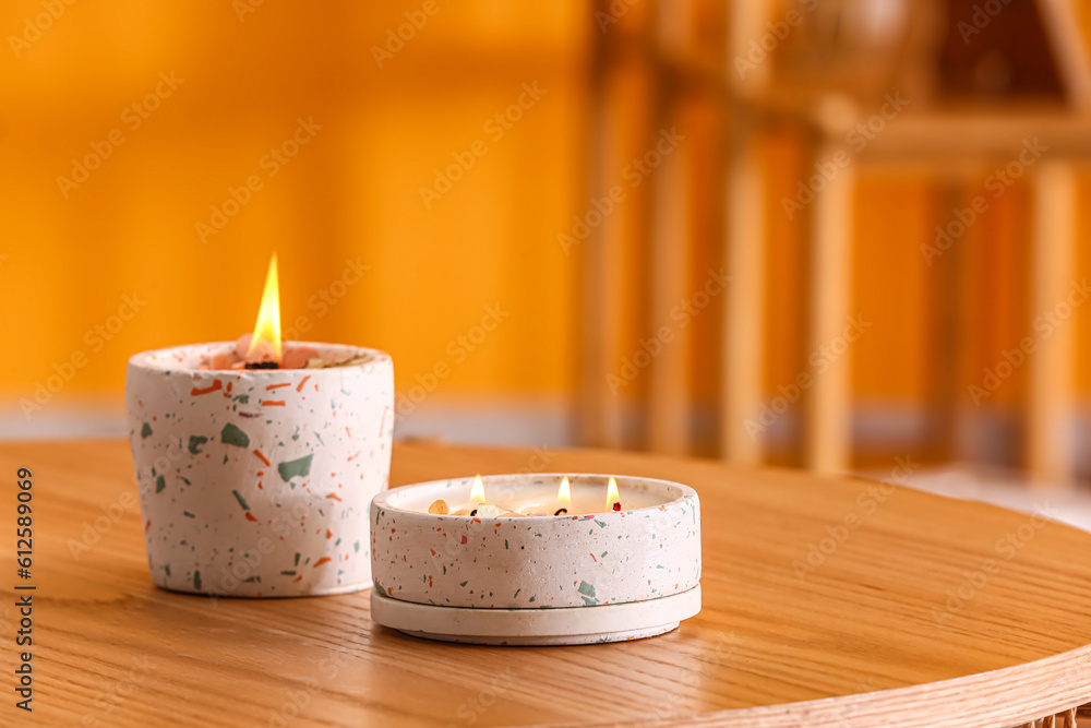 Holders with burning candles on table in room, closeup