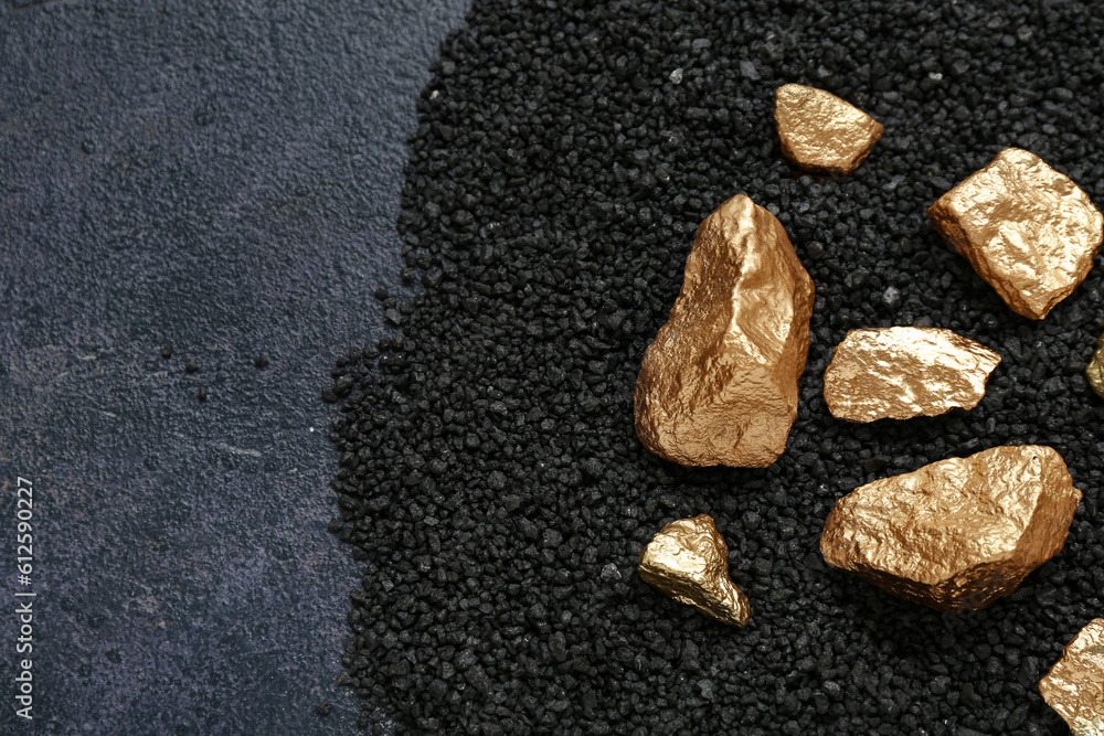 Golden nuggets and coal on dark background