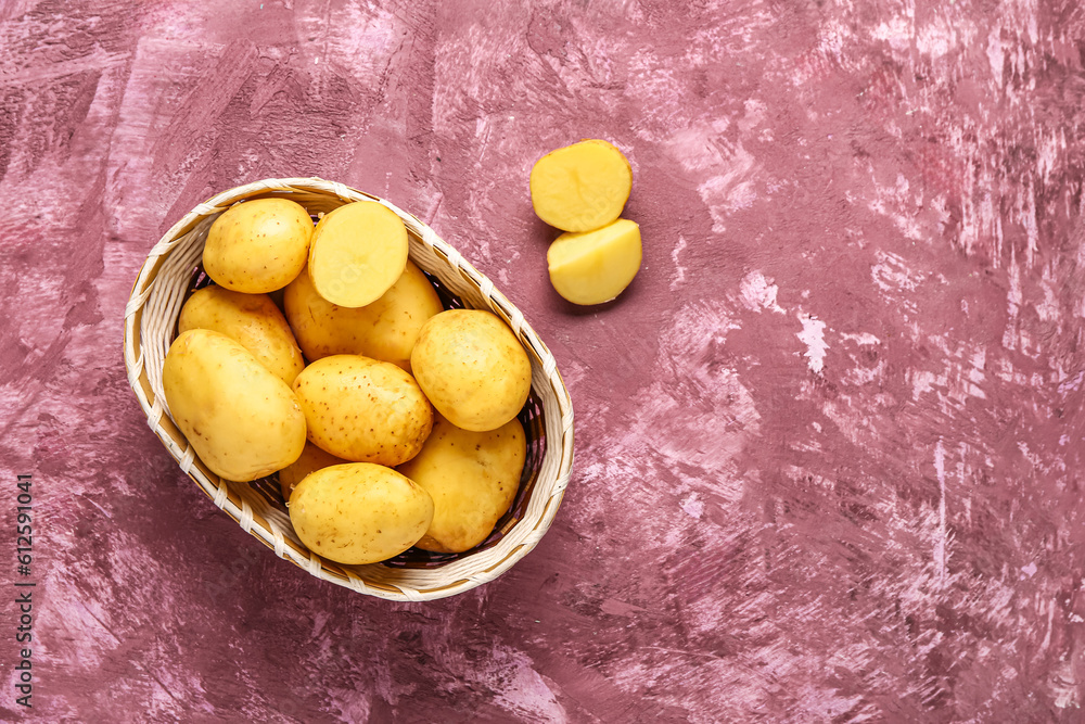 Wicker bowl with raw baby potatoes on purple background