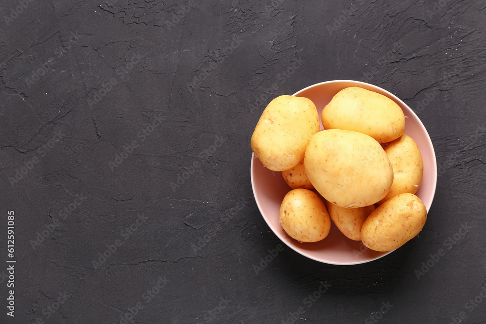 Bowl with raw baby potatoes on black background