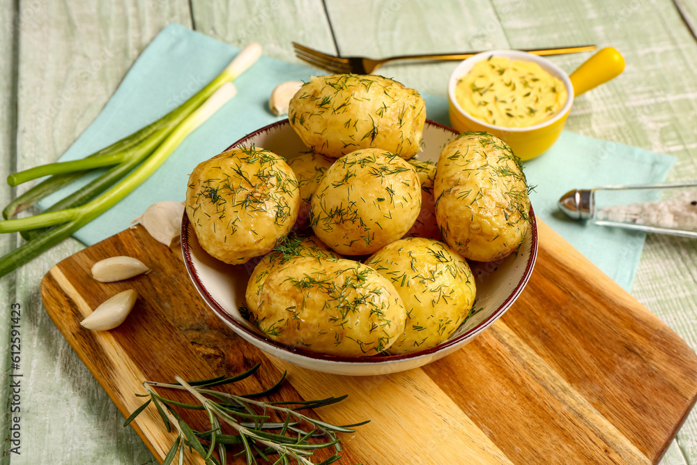 Plate of boiled baby potatoes with dill and scallion on green wooden background