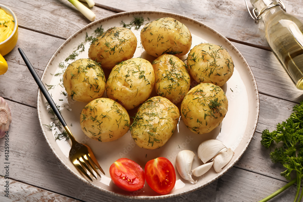 Plate of boiled baby potatoes with dill and tomatoes on grey wooden background