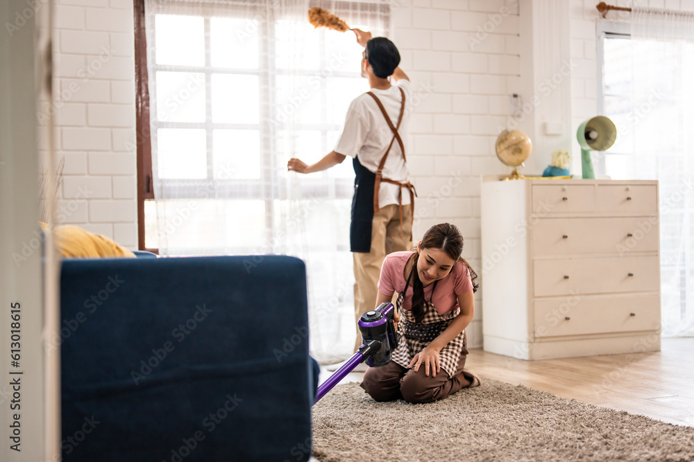 Asian attractive young man and woman cleaning house indoors together.