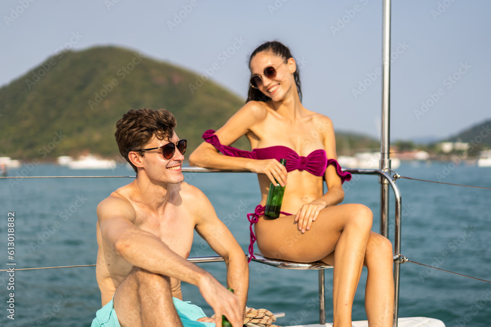 Caucasian young couple drinking beer while sitting on deck of yacht. 