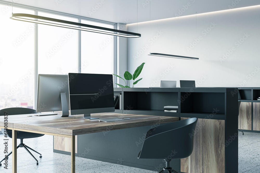 Perspective view of an open office interior with desks, computers, a concrete floor, and white walls