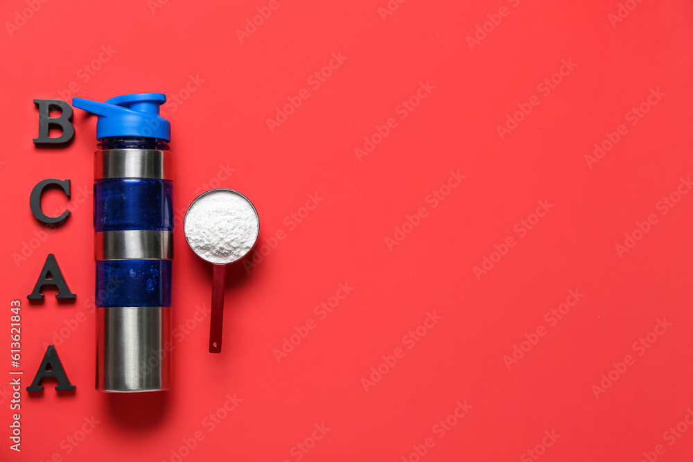 Bottle of water, letters BCAA and scoop with amino acid supplement on red background