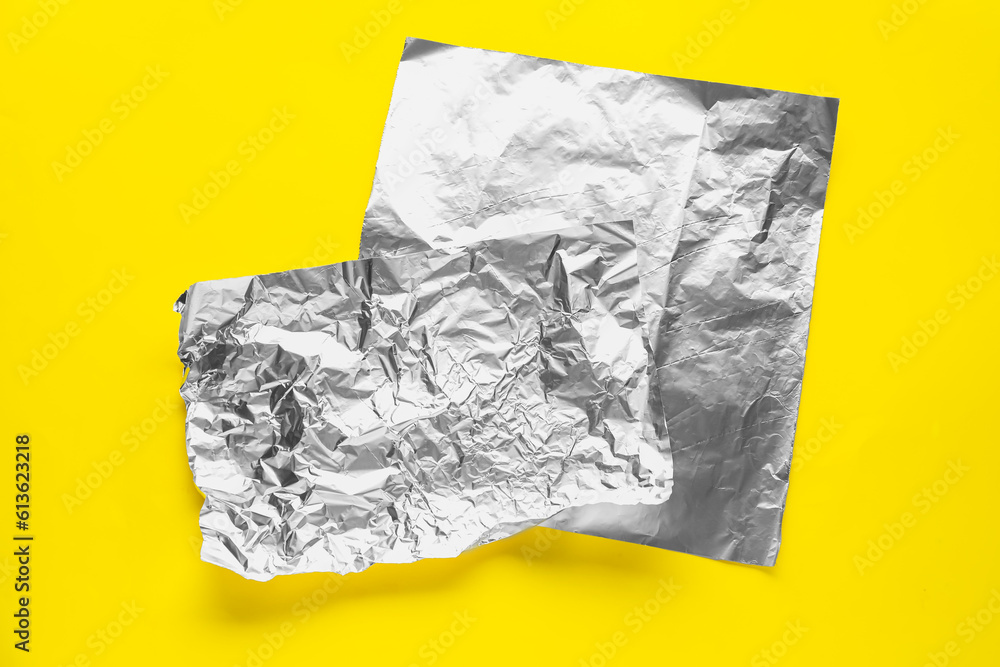 Sheets of aluminium foil on yellow background