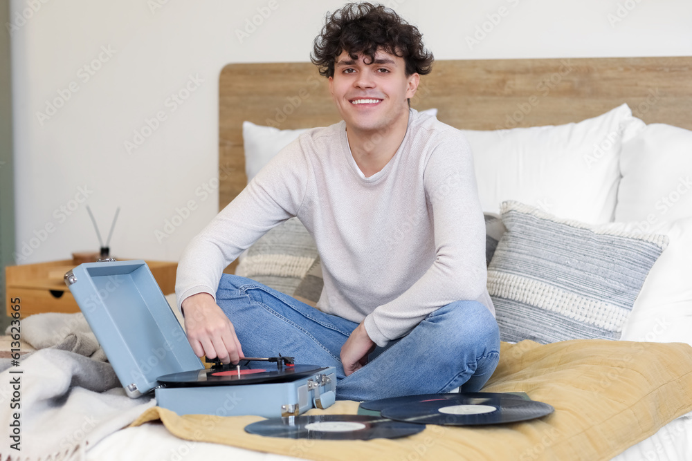 Young man with record player in bedroom