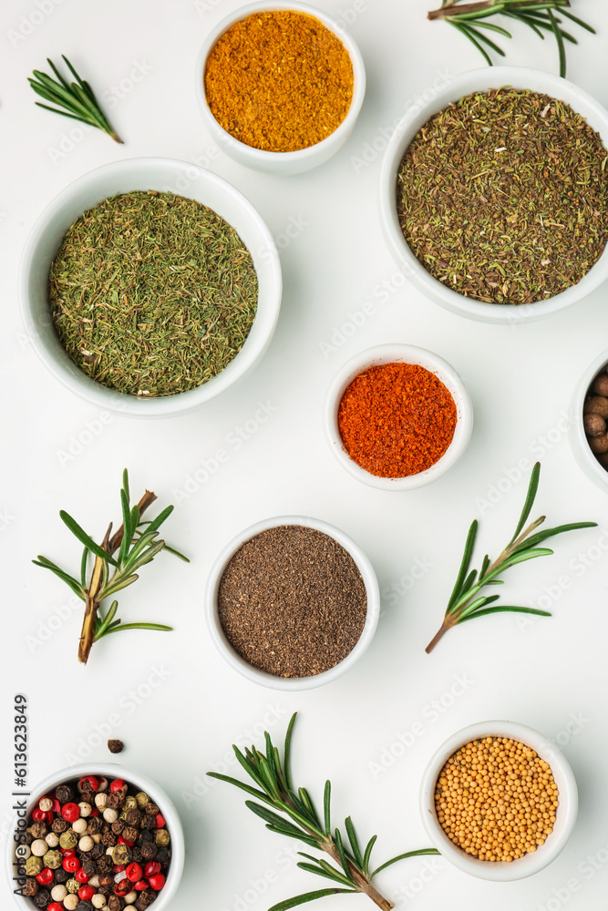 Composition with bowls of different spices and rosemary on light background