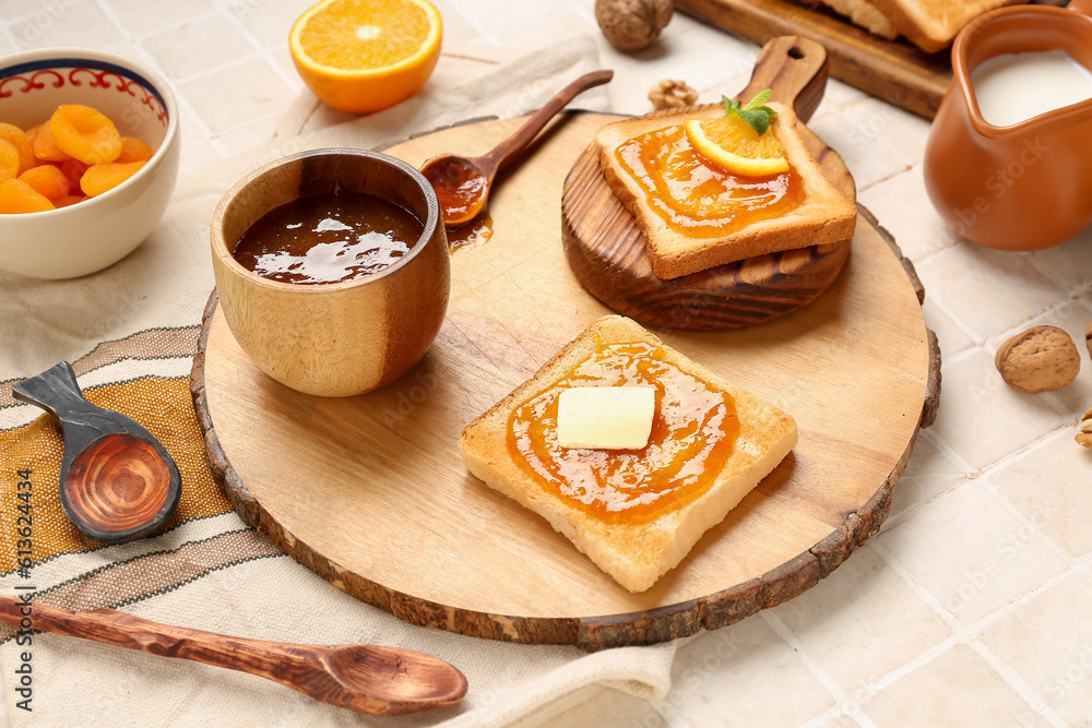 Wooden boards of tasty toasts with apricot jam on light tile background