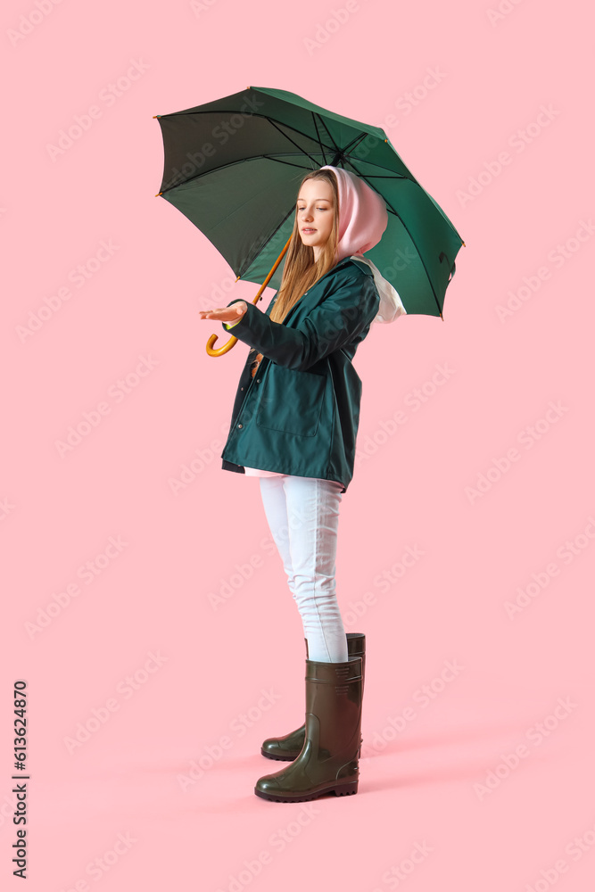 Teenage girl with green umbrella on pink background