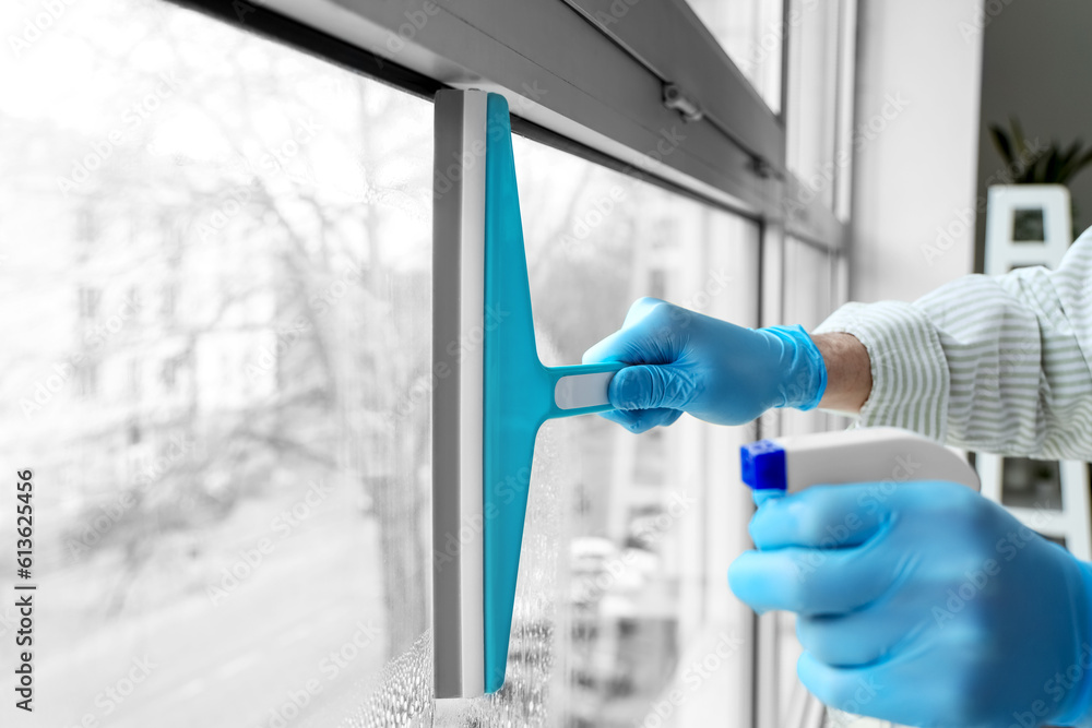 Male janitor cleaning window in room, closeup