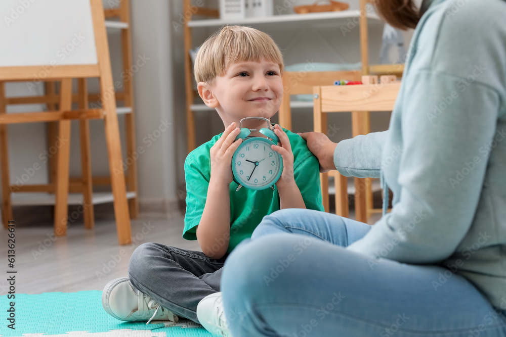 Little boy with alarm clock and nanny at home