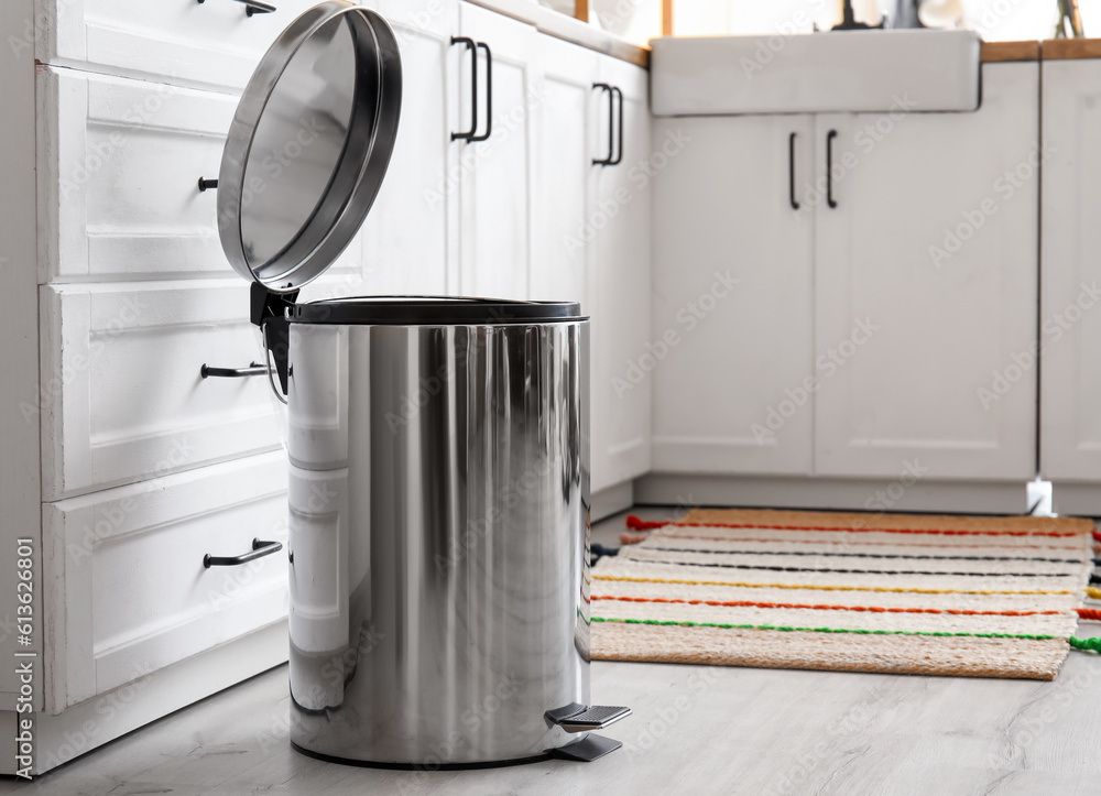 Opened metallic trash bin on floor in modern kitchen