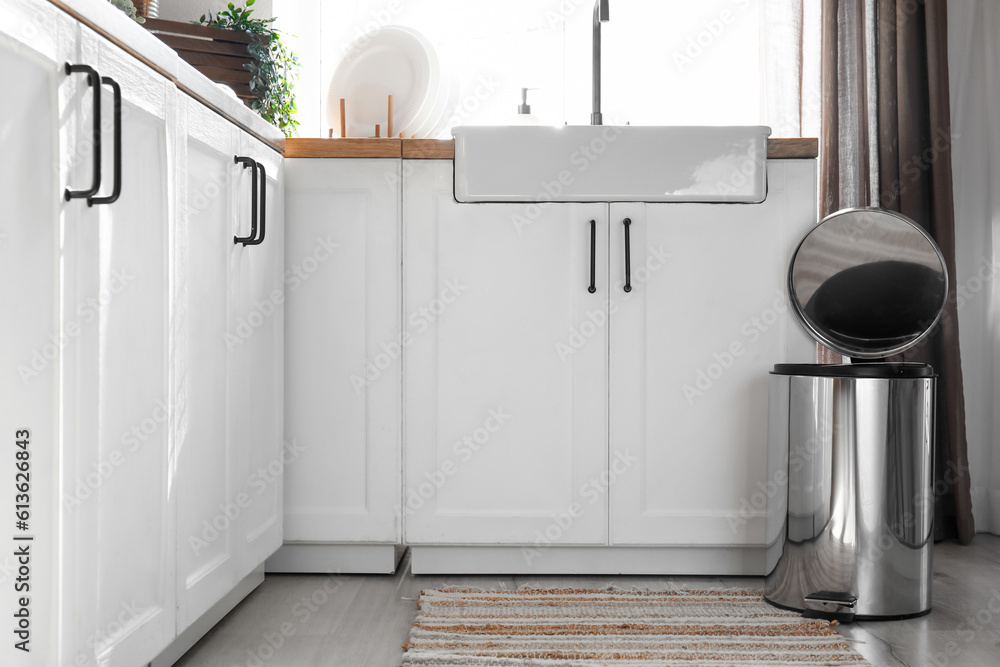 Opened metallic trash bin on floor in modern kitchen