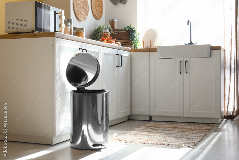 Opened metallic trash bin on floor in modern kitchen