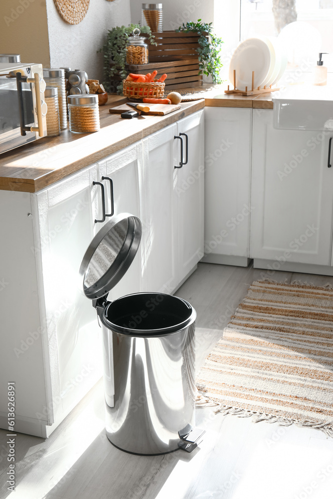 Opened metallic trash bin on floor in modern kitchen