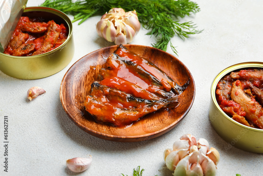 Composition with canned fish in tomato sauce, dill and garlic on white table