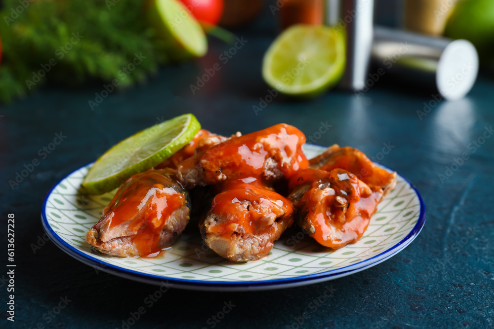 Plate with canned fish in tomato sauce on dark table