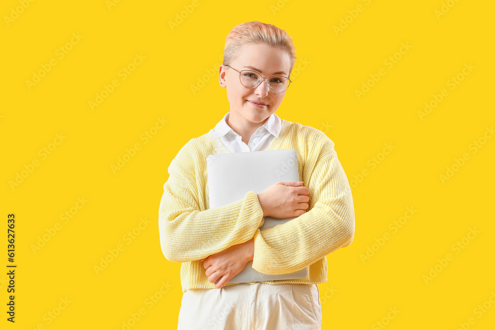 Female student with laptop on yellow background