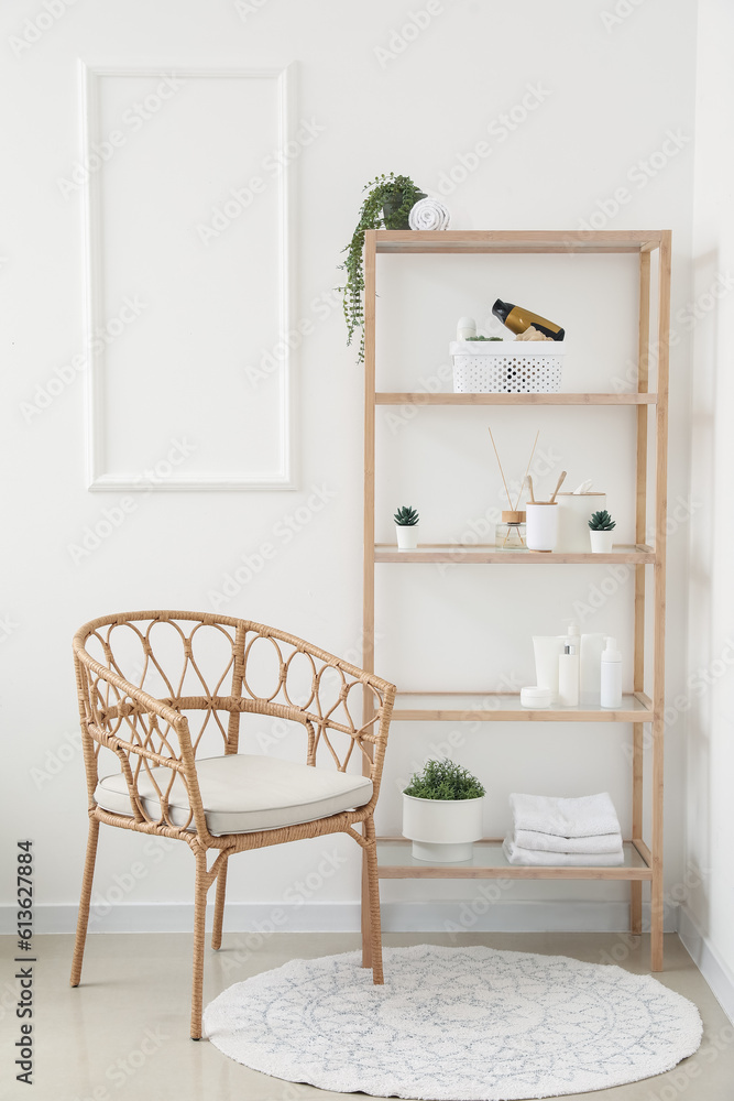 Shelving unit with bath accessories, houseplants and armchair in light room