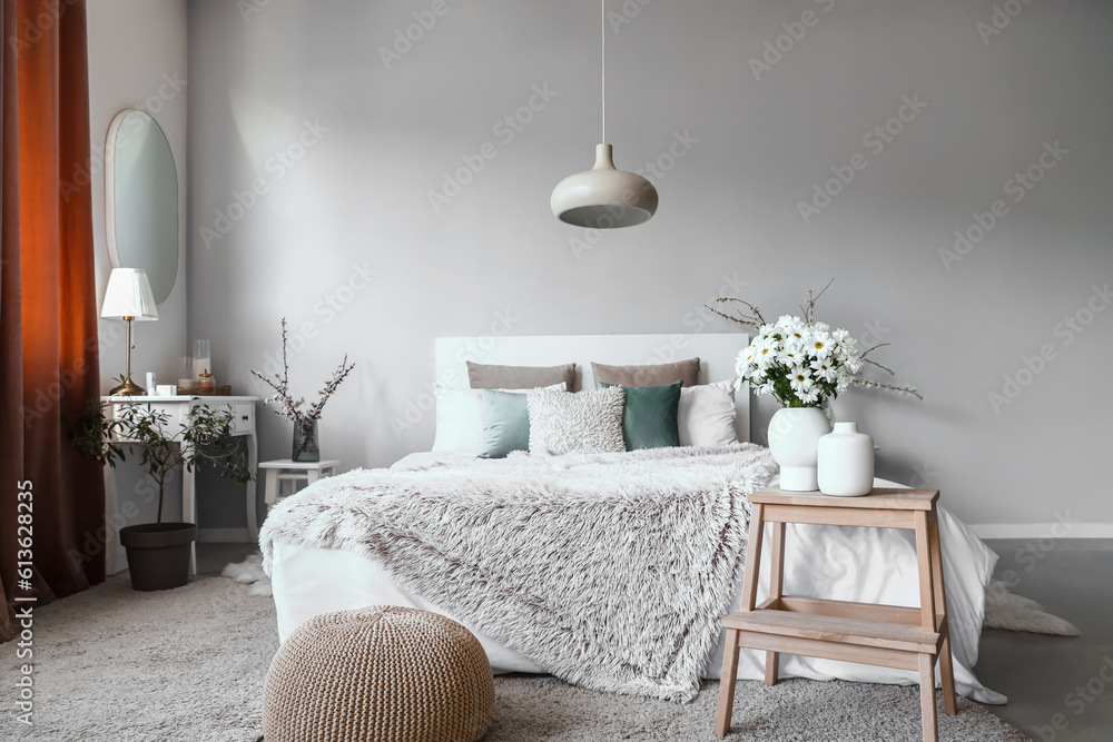 Interior of cozy bedroom decorated with chrysanthemum flowers and blooming tree branches