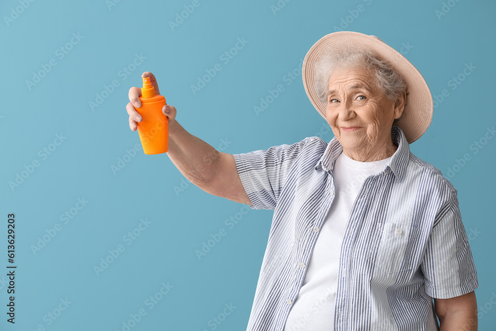 Senior woman with sunscreen cream on blue background