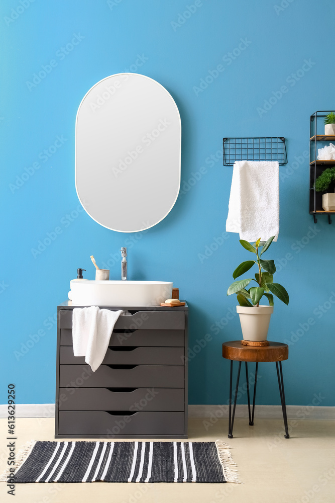 Interior of bathroom with sink on dressing table, mirror and houseplant