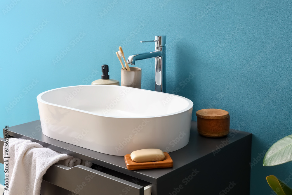 Sink and bathing accessories on dressing table near blue wall