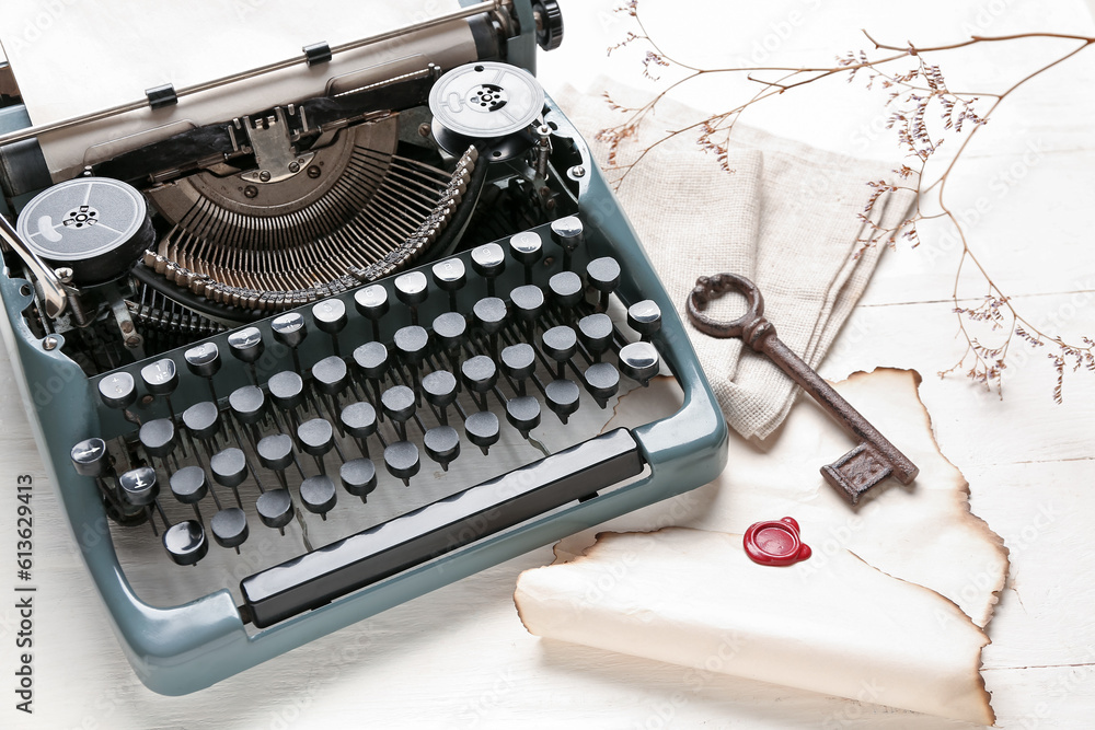 Composition with vintage typewriter, key, old parchment and blooming tree branch on white wooden tab