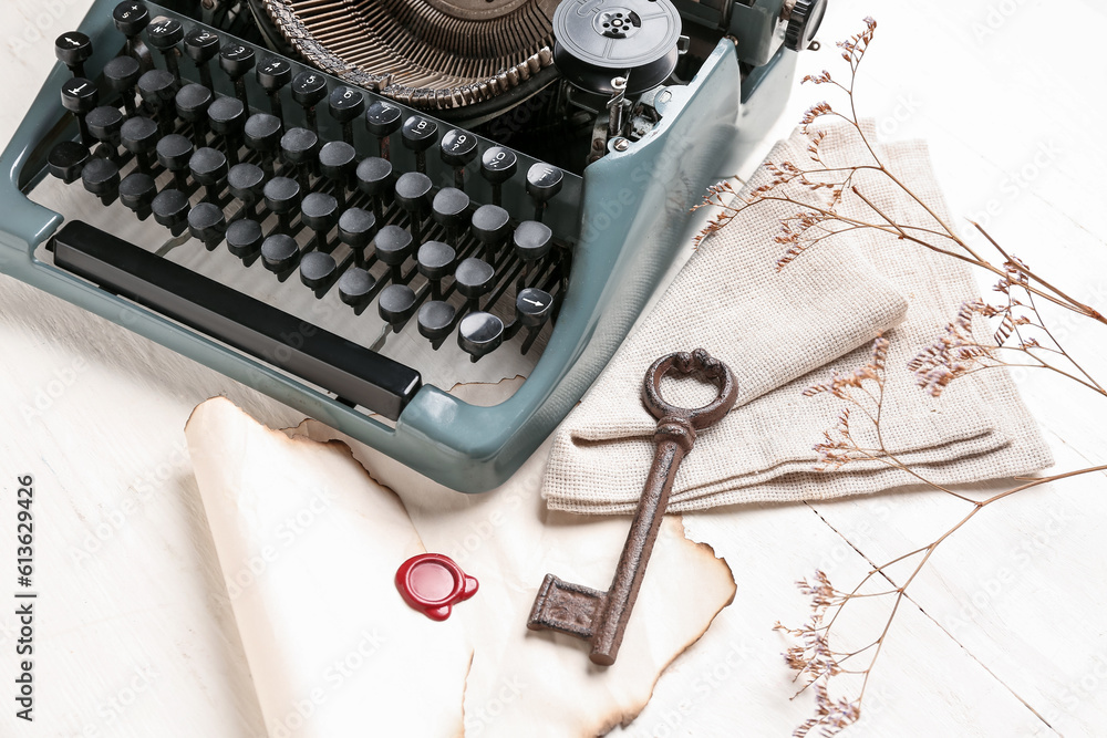 Composition with vintage typewriter, key, old parchment and blooming tree branch on white wooden tab