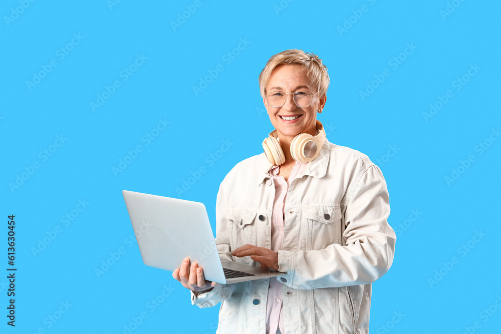 Mature female programmer working with laptop on blue background