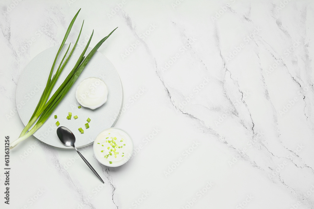 Bowls of tasty sour cream with green onion on white marble background