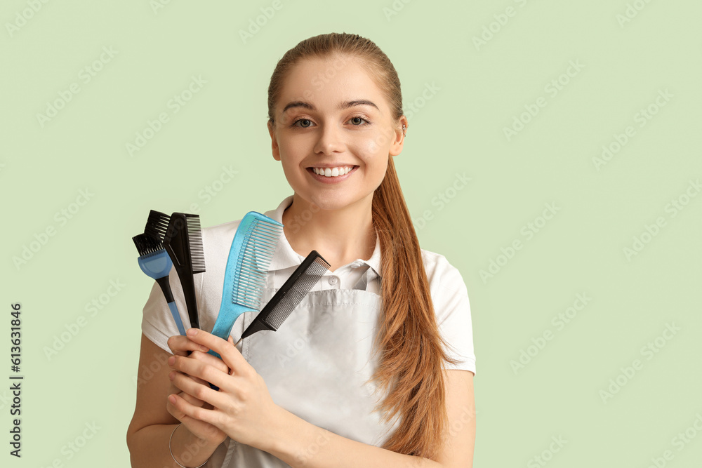 Female hairdresser with brushes on green background