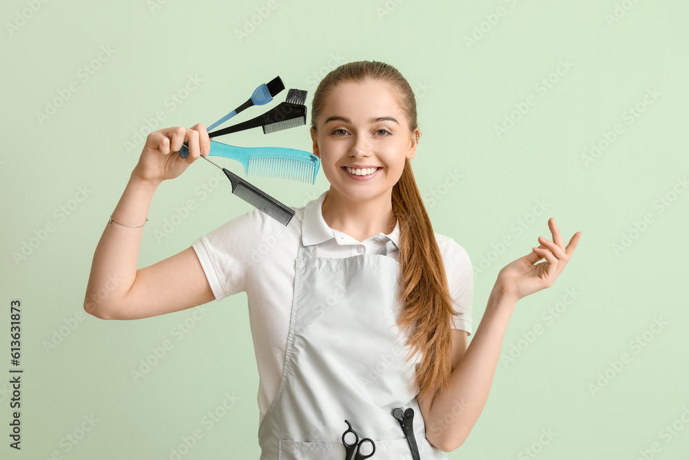 Female hairdresser with brushes on green background