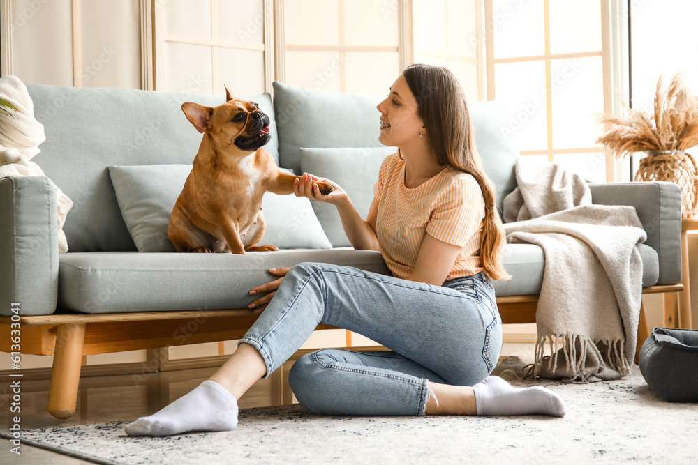 Young woman with cute French bulldog at home