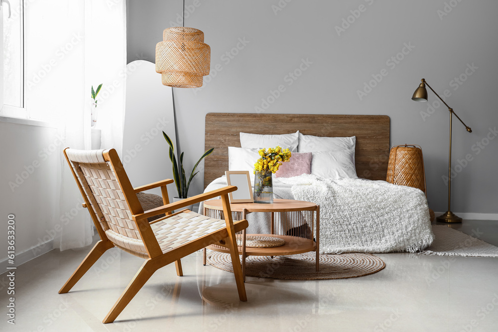 Interior of light bedroom with armchair, table and mirror