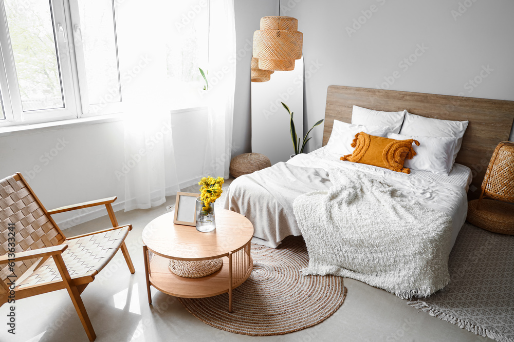 Interior of light bedroom with armchair, table and mirror