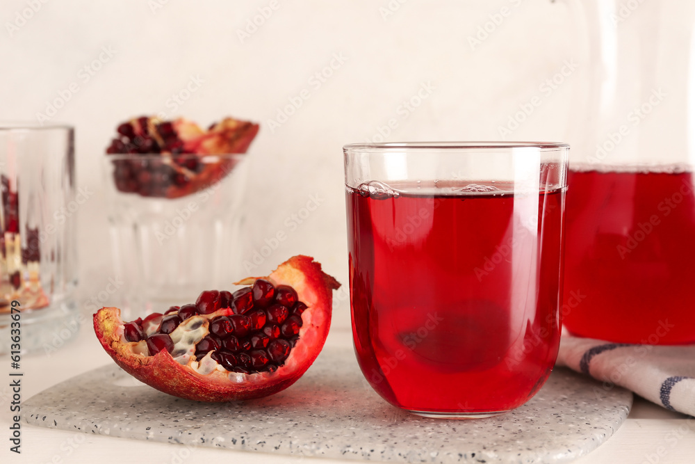 Jug and glass of fresh pomegranate juice on white wooden table