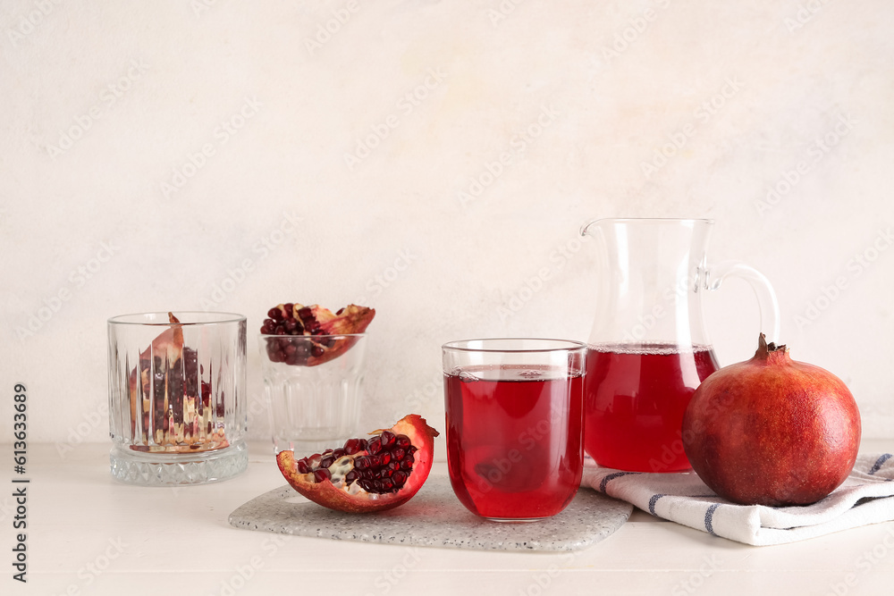 Jug and glass of fresh pomegranate juice on white wooden table