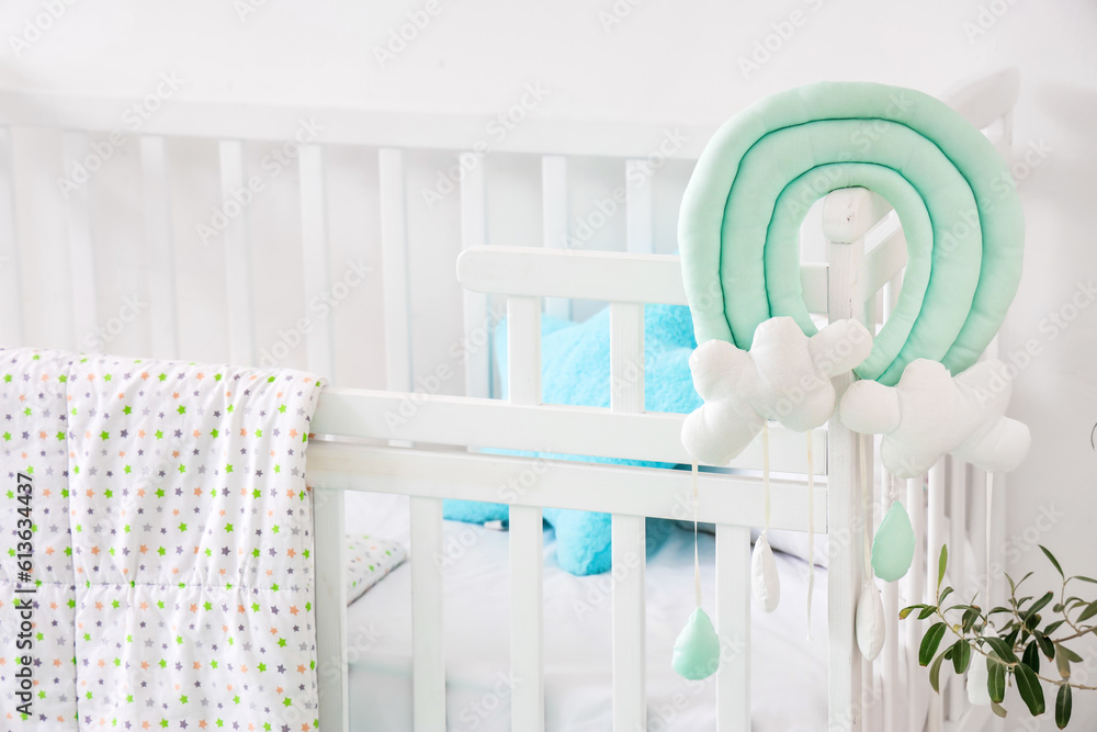 White baby bed with toys in stylish childrens room