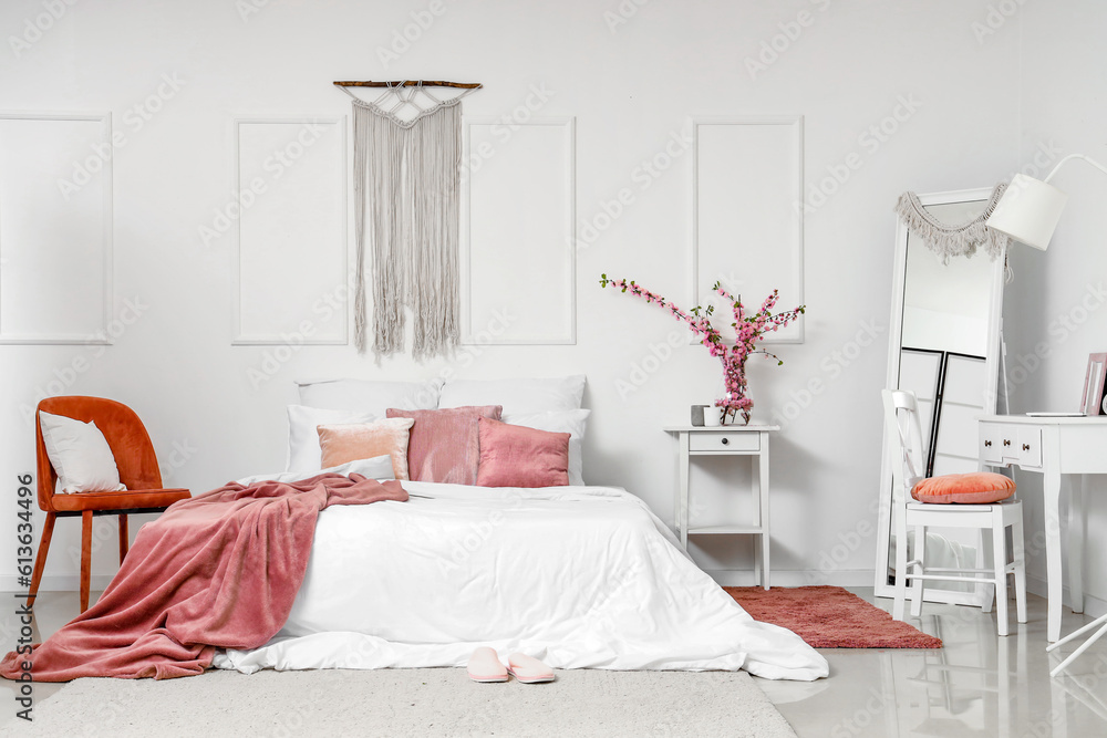 Interior of cozy bedroom with blooming tree branches in vase