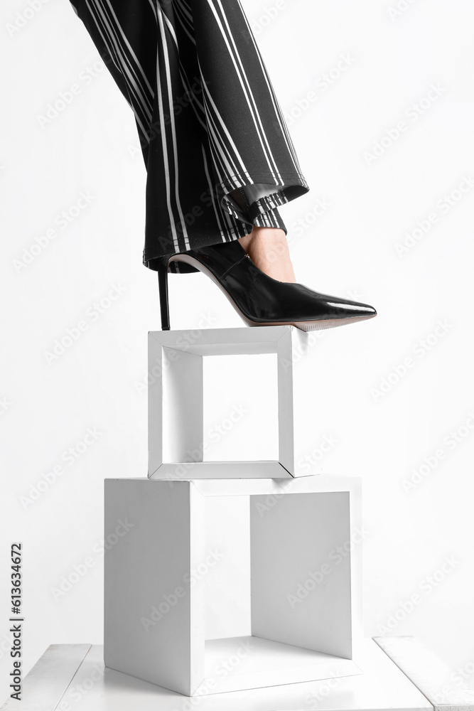 Female leg in black heels standing on stand against white background