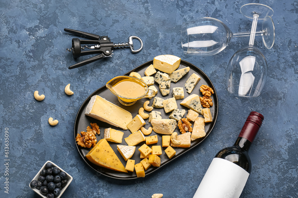 Pieces of tasty cheese, honey and wine glasses on blue background