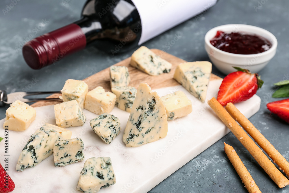 Board with pieces of tasty cheese on grey background