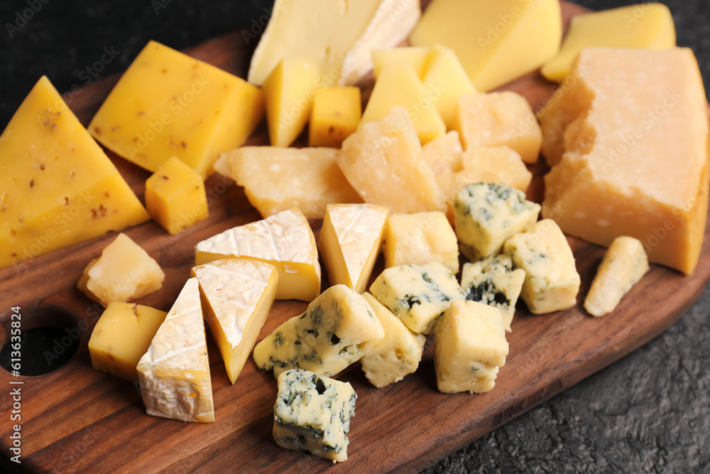 Wooden board with pieces of tasty cheese on table, closeup