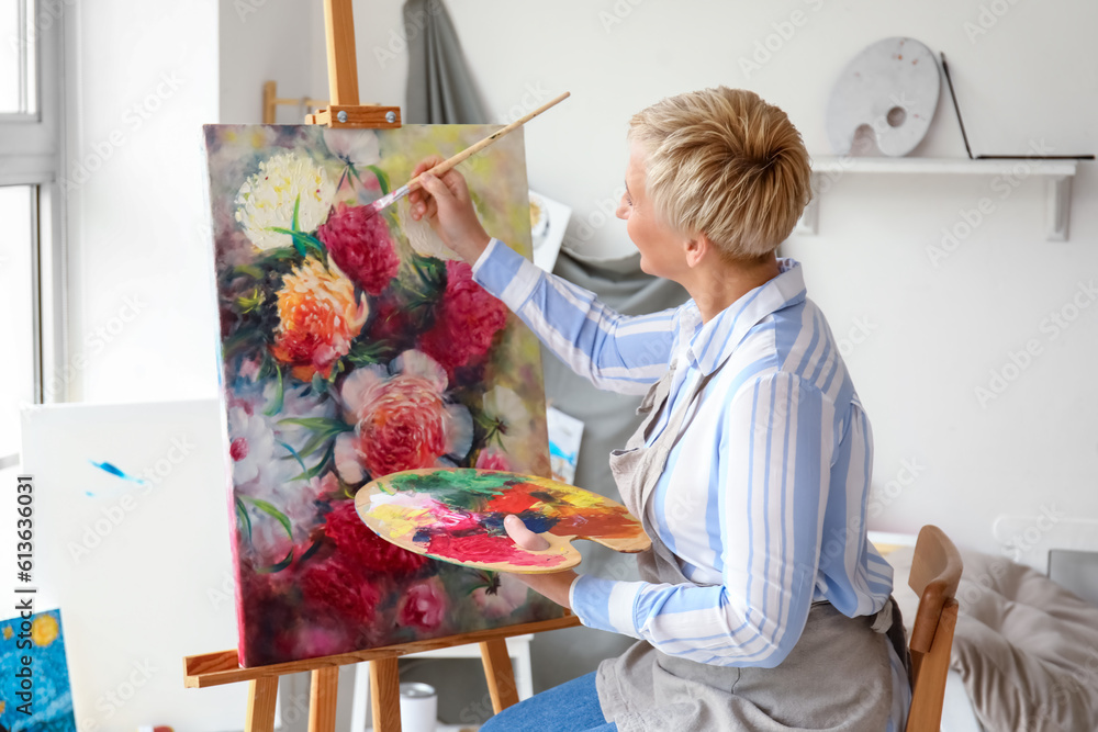 Mature female artist painting picture in  workshop