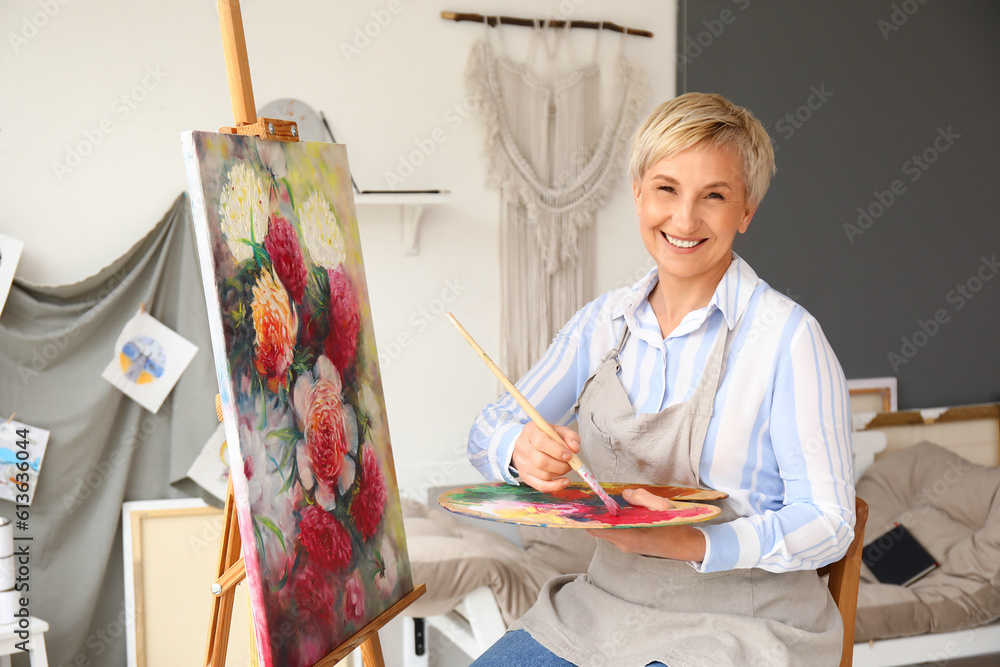 Mature female artist painting picture in  workshop